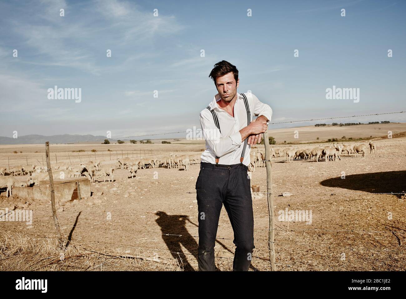 Portrait de l'homme dans des vêtements à l'ancienne avec troupeau de moutons dans l'enceinte Banque D'Images