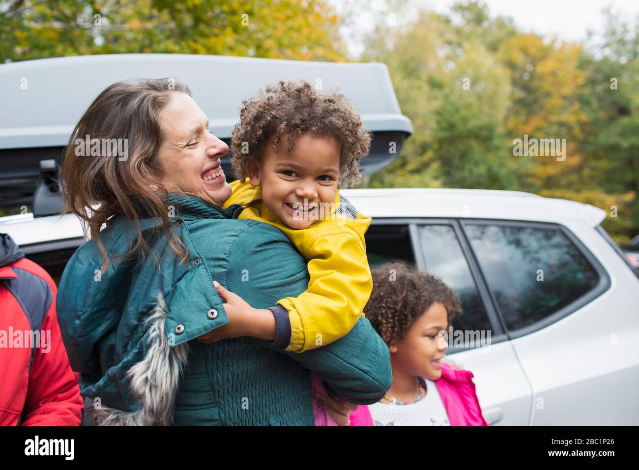 Portrait bonne mère tenant la fille à l'extérieur de la voiture dans le parking Banque D'Images