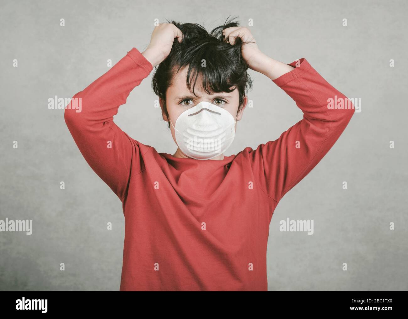 Coronavirus.enfant avec masque de visage désespéré pour la quarantaine sur fond gris Banque D'Images