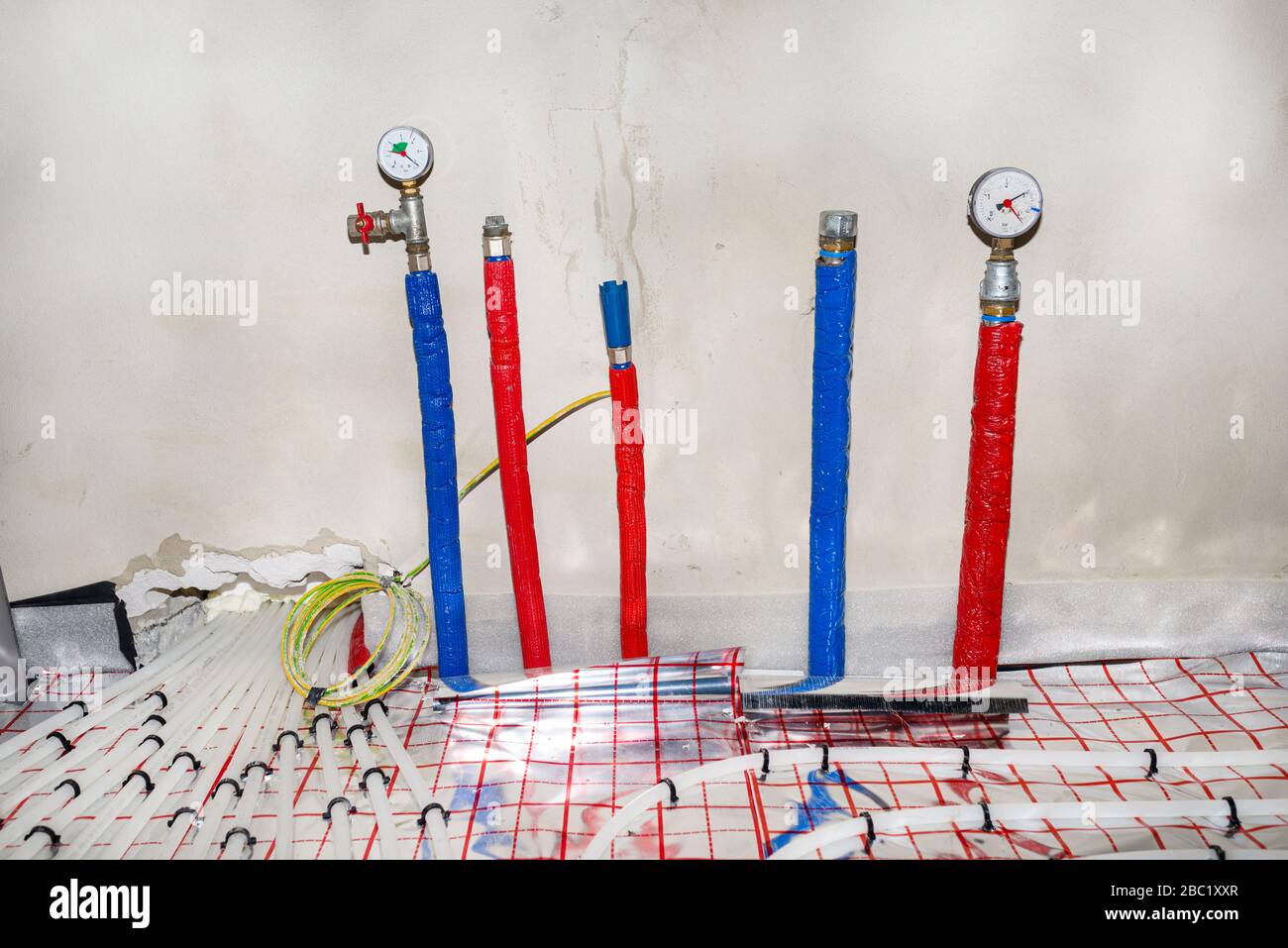 Tuyaux avec de l'eau chaude et froide sortant du plancher et manomètres