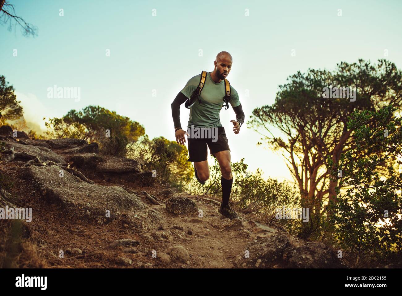 Homme courir sur un sentier rocheux de montagne. Coureur masculin en pente dure le matin. Banque D'Images
