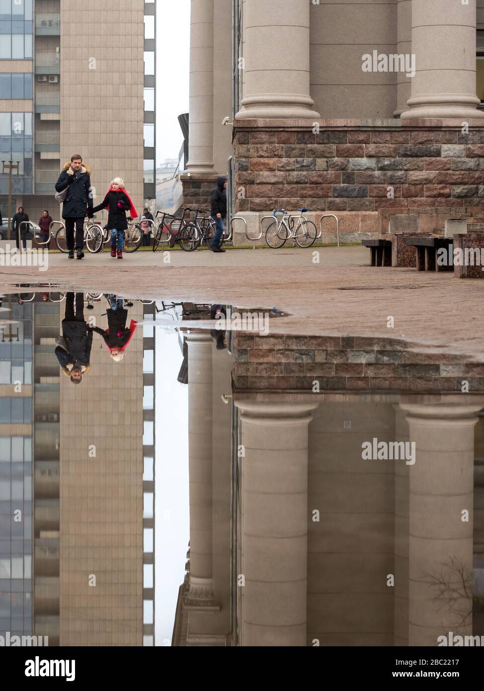 Vilnius/Lituanie - 07 03 2020: Une fille avec son père allant à la ville pendant la foire de Saint-Casimir et leur réflexion dans l'eau Banque D'Images