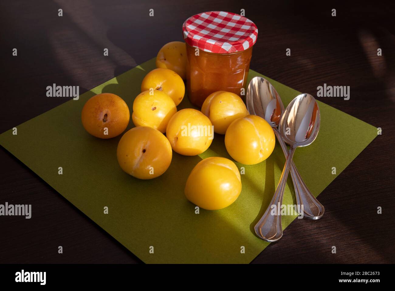 Gros plan de prunes jaunes et un pot de confiture sur fond en bois et vert Banque D'Images