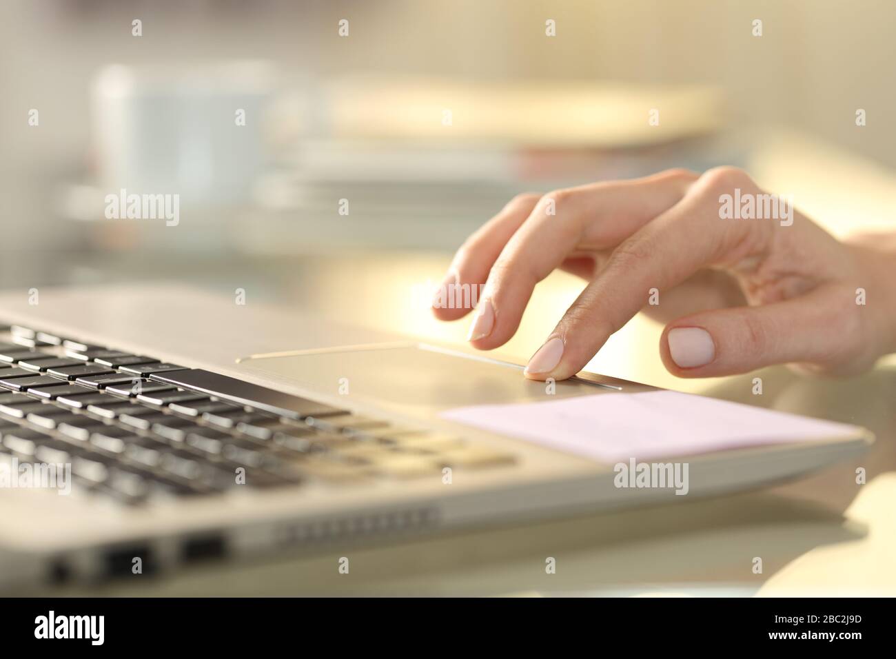 Gros plan sur la main d'une femme en appuyant sur le bouton du pavé tactile de l'ordinateur portable sur un bureau à la maison Banque D'Images