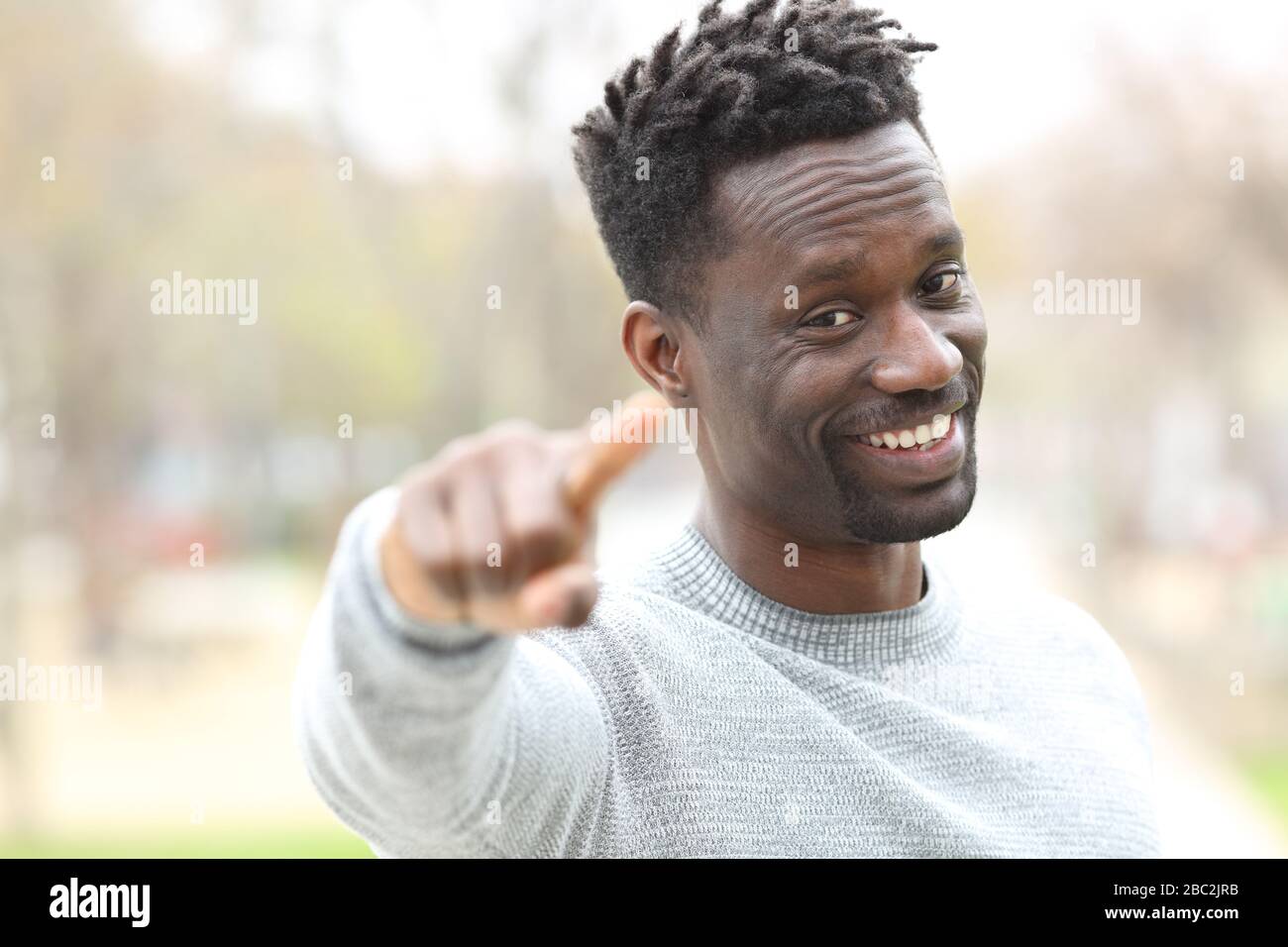 Heureux homme noir pointant à la caméra debout dans un parc Banque D'Images