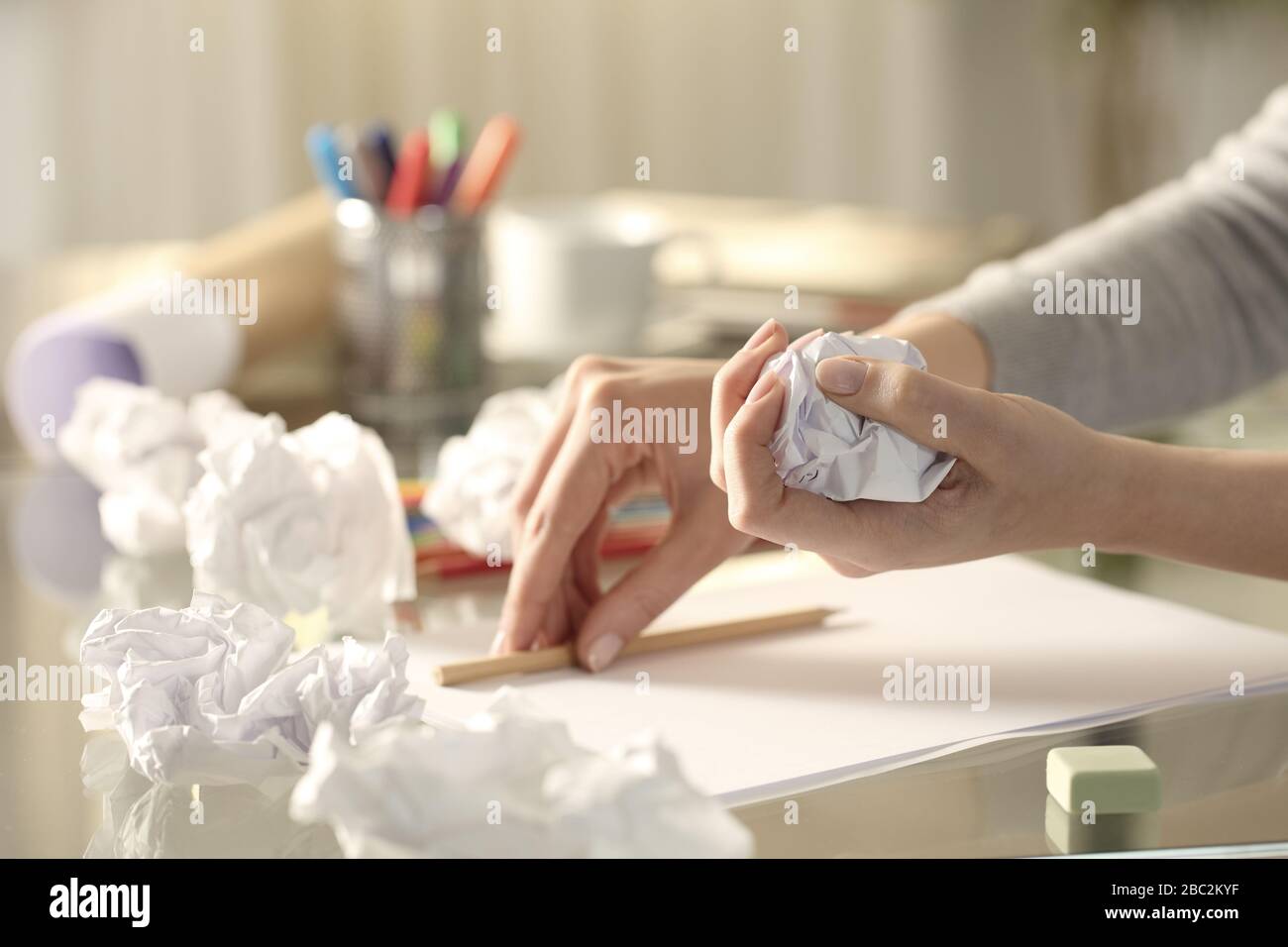 Gros plan sur les mains de la femme qui froissait un morceau de papier laissant le crayon sur le bureau à la maison Banque D'Images