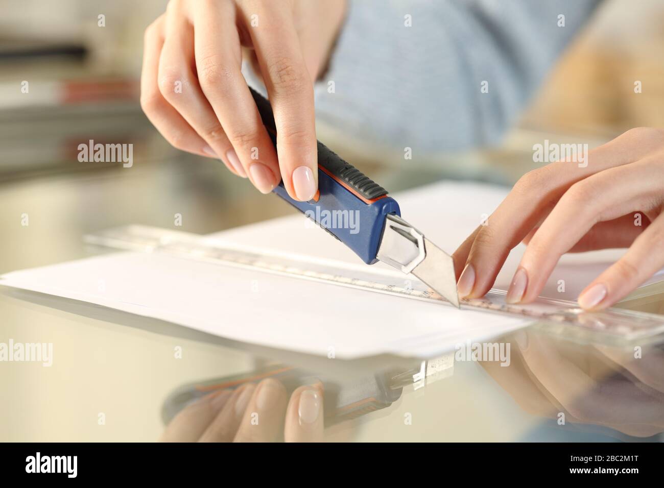 Gros plan sur les mains de la femme, avec couteau et règle assis sur un bureau à la maison Banque D'Images