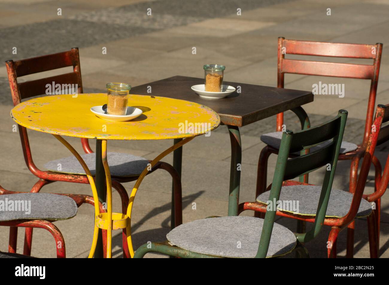 Ensemble coloré de sièges d'époque ou de grunge avec tables rondes et carrées en métal et chaises en métal dans la zone piétonne Banque D'Images