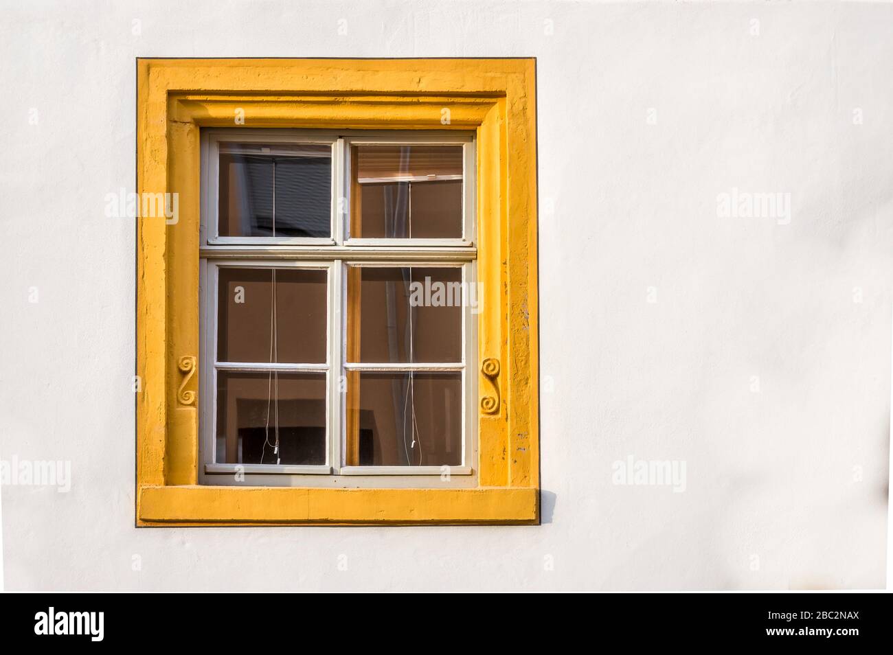 Fenêtre d'une maison restaurée à colombages partiellement plâtrée avec cadre en grès, décorée de couleur jaune Banque D'Images
