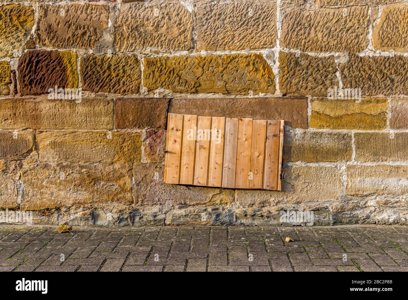 Mur de grès avec fenêtre de cave et arbre pour cave à terre ou à charbon, recouvert de panneaux en bois Banque D'Images