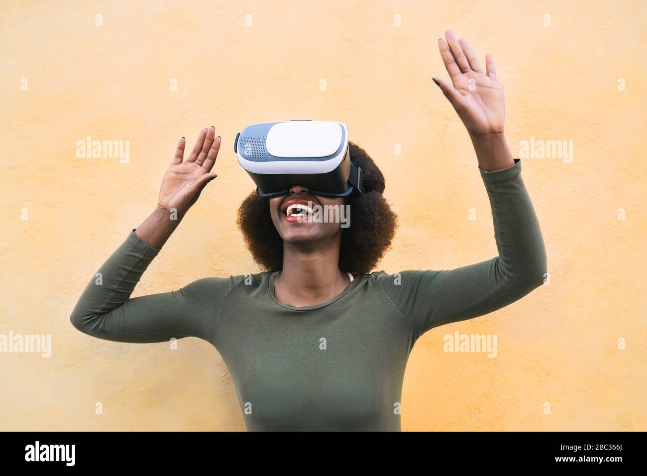 Une femme afro heureuse utilisant un casque de réalité virtuelle en extérieur - une fille branchée s'amusant avec la technologie innovante vr googles Banque D'Images