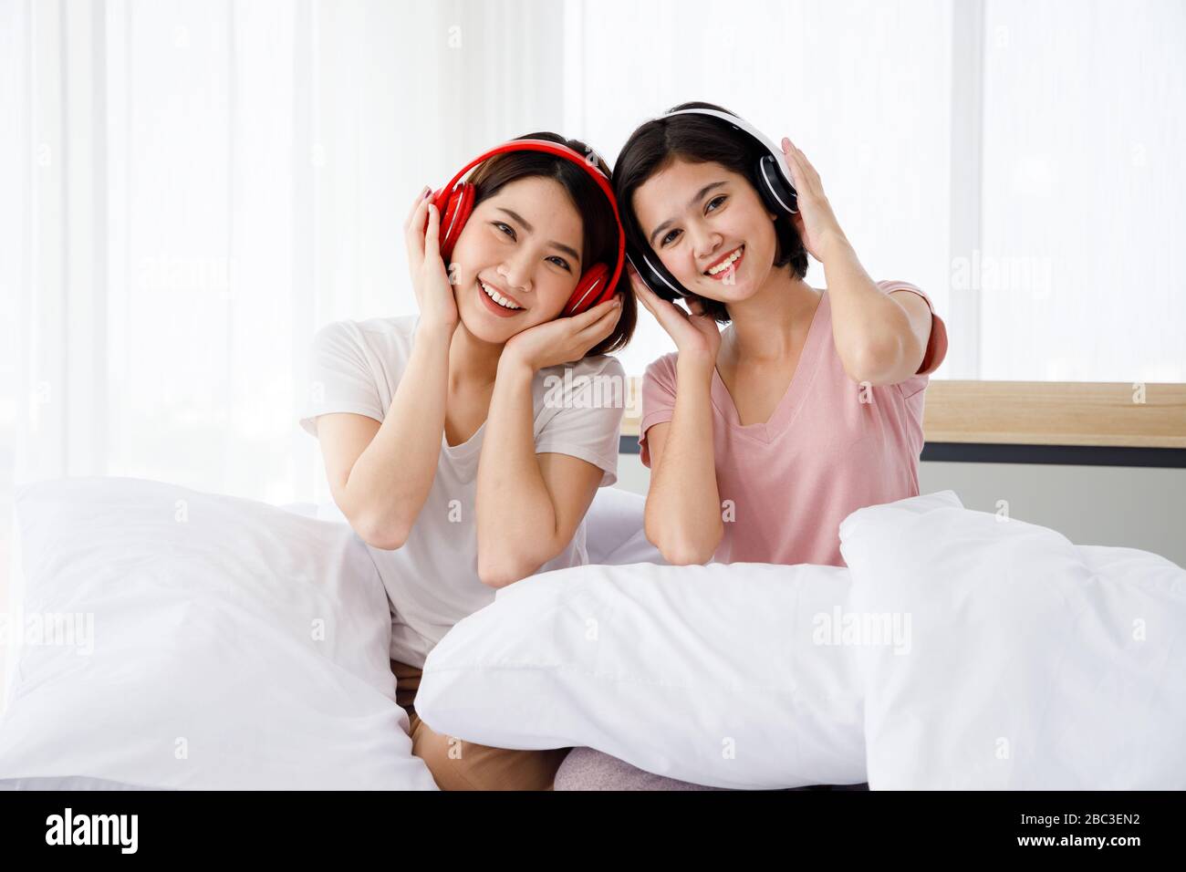 Deux femmes asiatiques heureuses portent un casque et apprécient les musiques ou les chansons qu'elles aiment dans la chambre. Banque D'Images