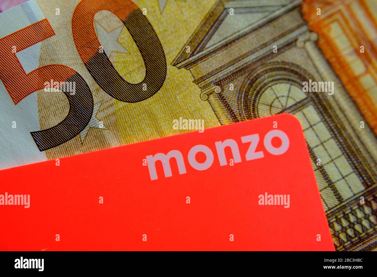 Carte bancaire Monzo placée au-dessus de 50 billets de banque en euros. Gros plan de la photo. Banque D'Images