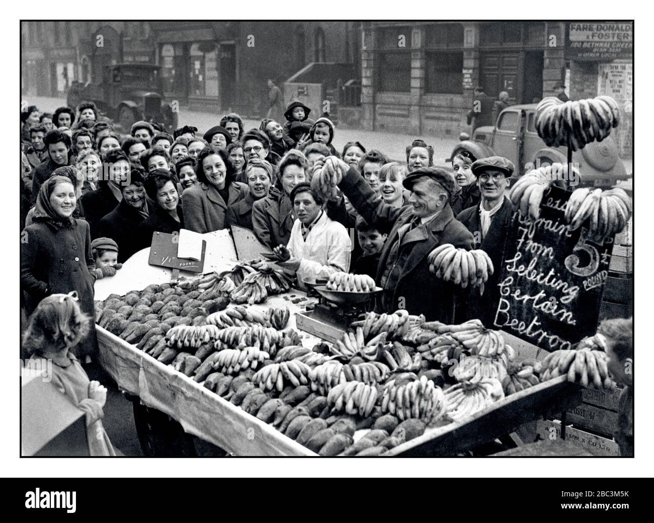 Vintage archive 1940s Food Rationing Market Stall 1946 après la guerre WW2 bananes fraîches et Beetroot en vente dans l'est de Londres avec une foule de clients très enthousiastes autour de la stalle Bethnal Green London Royaume-Uni Banque D'Images