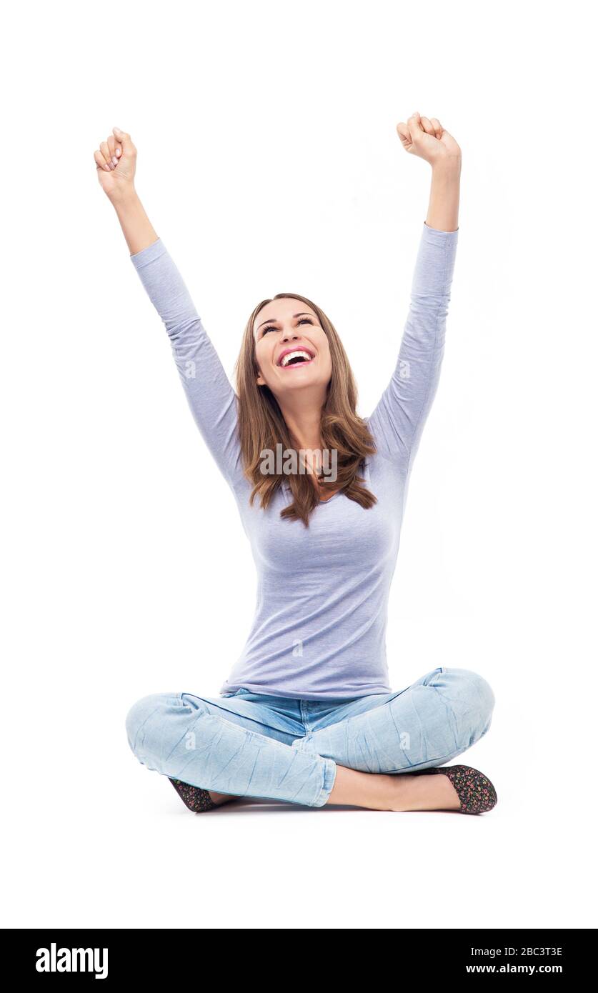 Jolie femme assise avec bras levés Banque D'Images