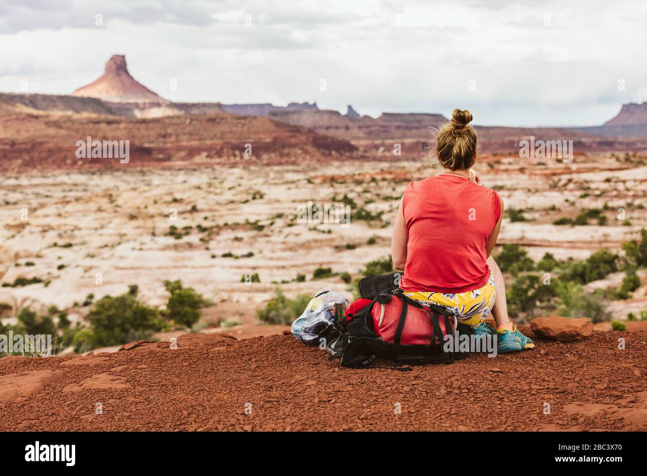 une femme sueur s'assoit sur un sac à dos pendant une randonnée avec vue sur le désert Banque D'Images