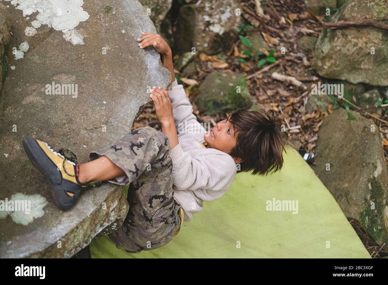 Petit garçon grimpant sur un rocher à l'extérieur Banque D'Images