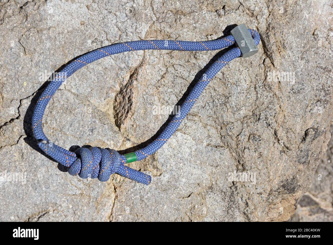 cale hexagonale traditionnelle de protection de l'escalade s'affaissant avec un cordon bleu assis sur une roche Banque D'Images