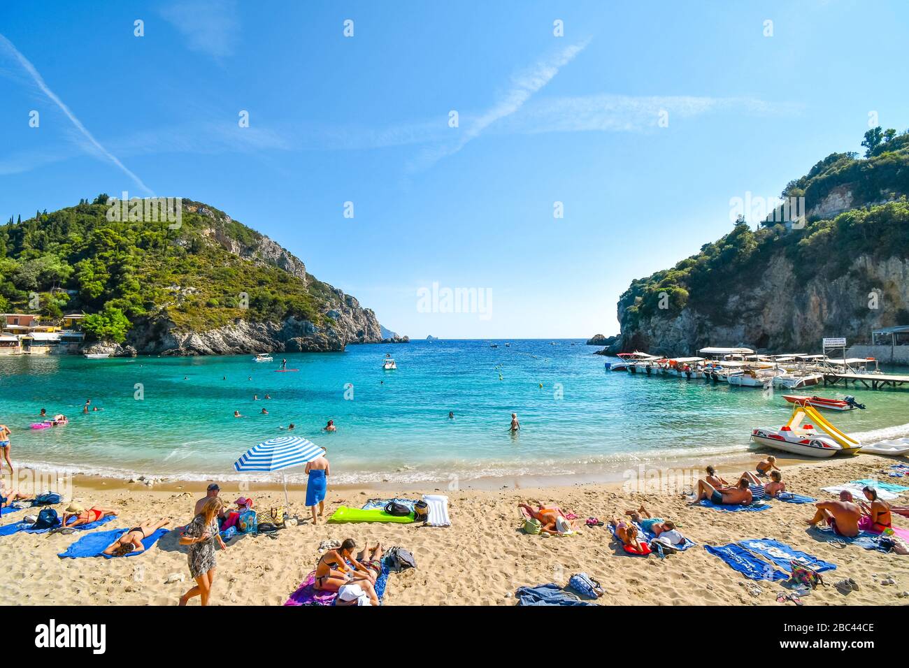 Les touristes se détendent dans les eaux claires de la plage de sable de Palaiokastritsa et de la baie sur l'île égéenne de Corfou, Grèce. Banque D'Images