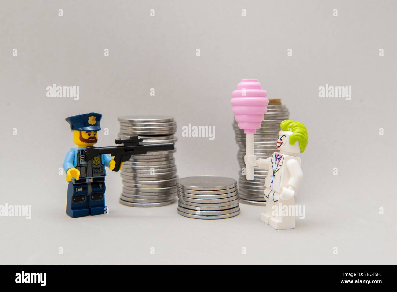 Florianopolis, Brésil, 28 mars 2020: Policier visant son arme à feu au joker à côté d'une pile de pièces. Le crime ne paie pas. Les figurines LEGO sont des hommes Banque D'Images