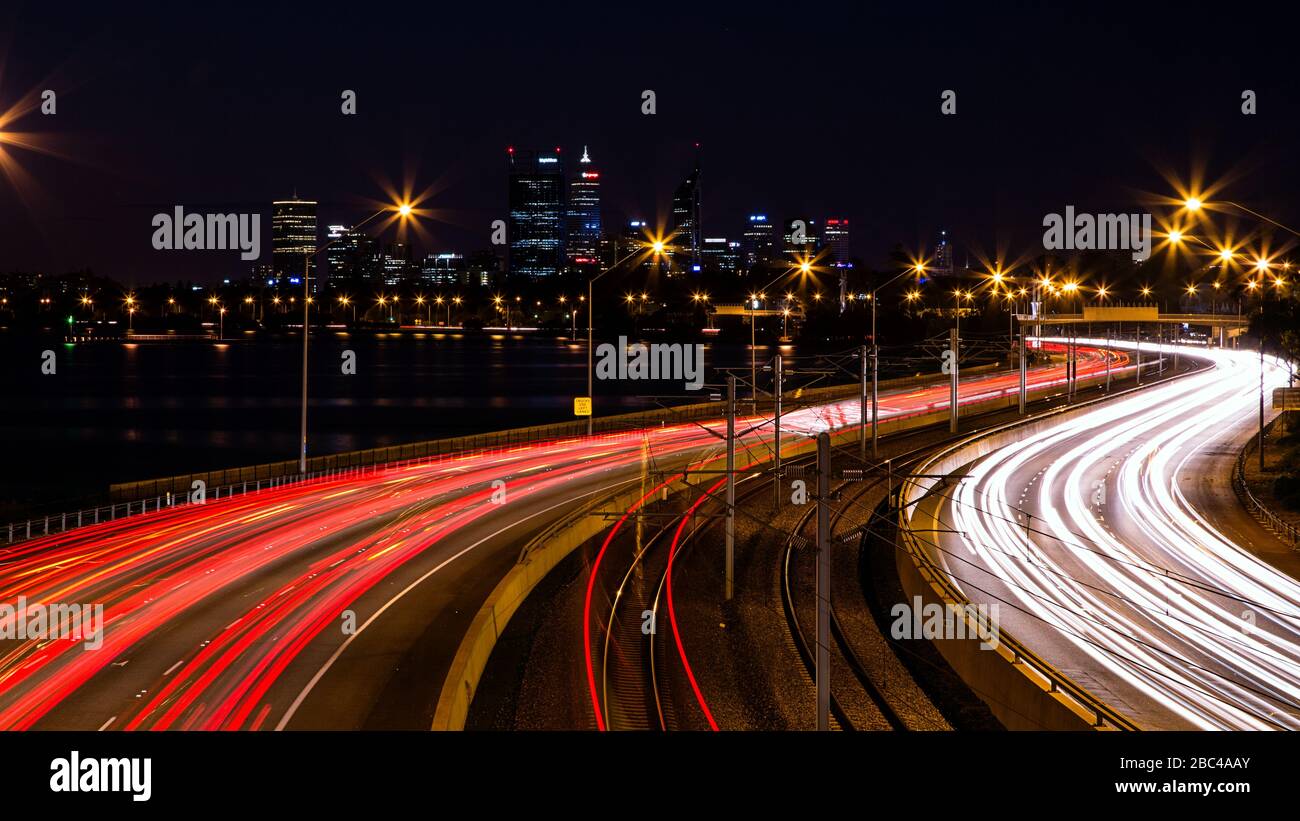 Des sentiers légers sur l'autoroute Perth Kwinana avec la ville de Perth en arrière-plan Banque D'Images