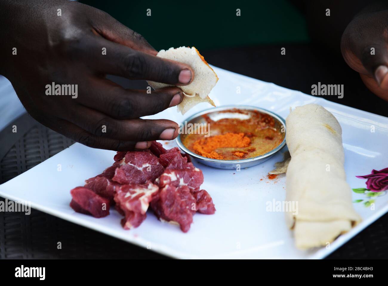 Un éthiopien mangeant Injera être pneu siga ( injera avec la viande brute ) Banque D'Images