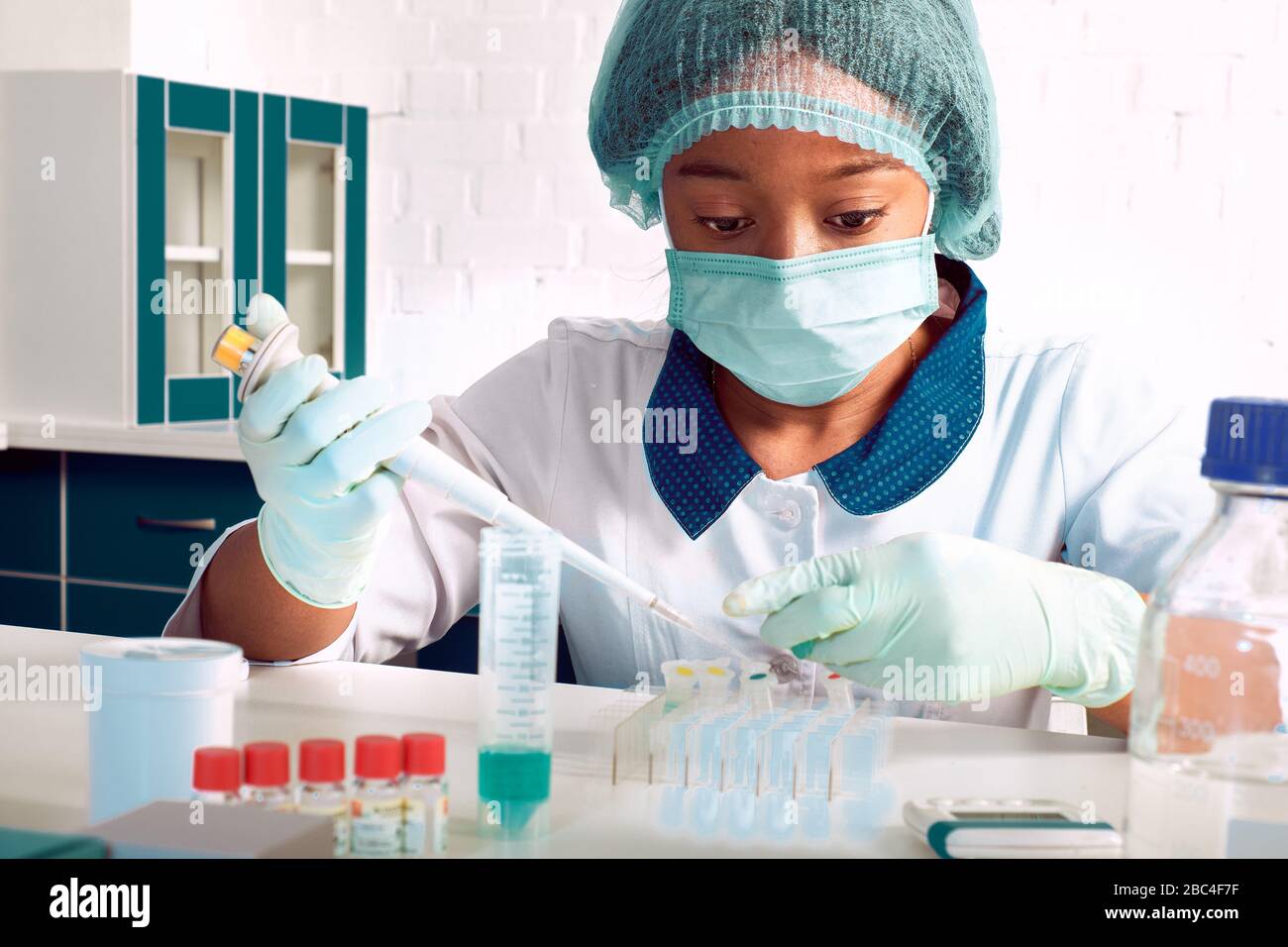 Test PCR pour coronavirus. La jeune femme africaine, scientifique ou médique en pelage blanc et chapeau, effectue un test des acides nucléiques pour détecter le SRAS-CoV-2 en pati Banque D'Images