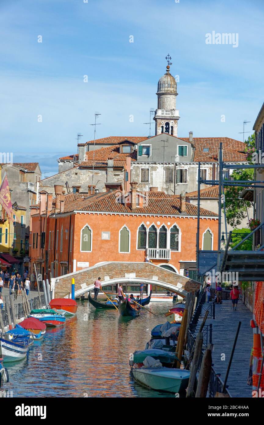 Gondoliers passant sous un petit pont sur un canal vénitien Banque D'Images