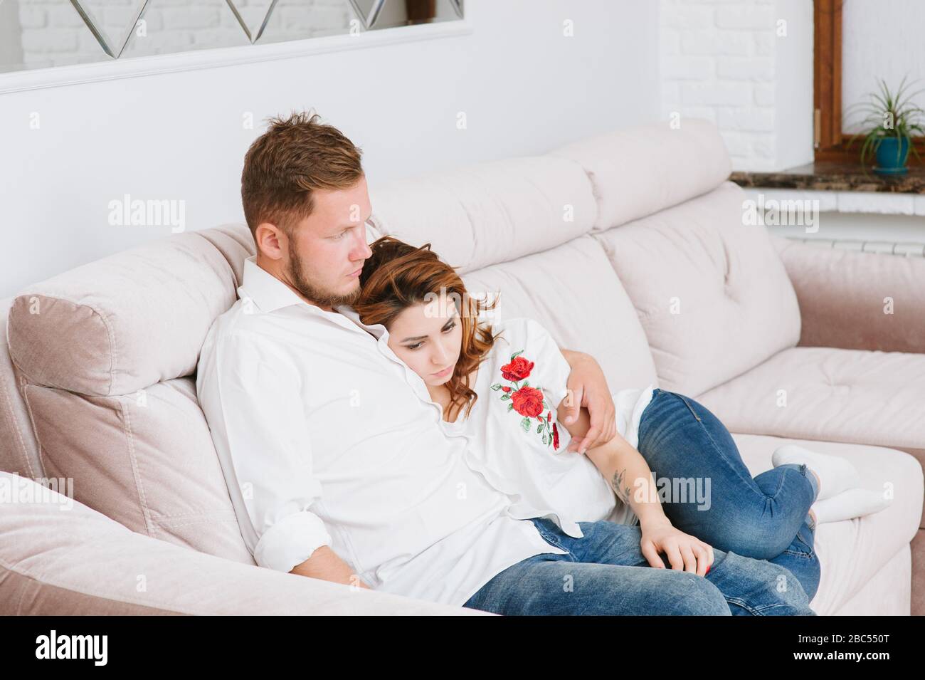 concept d'auto-isolation de deux jeunes hommes et femmes assis sur un canapé à la maison à l'intérieur étant triste Banque D'Images