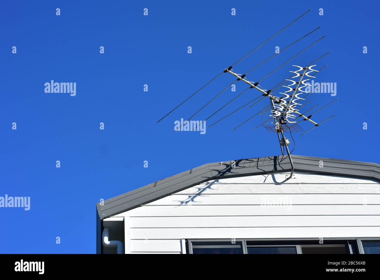 Antenne multicanal au-dessus du toit de la maison en bois avec ciel bleu clair en arrière-plan. Banque D'Images