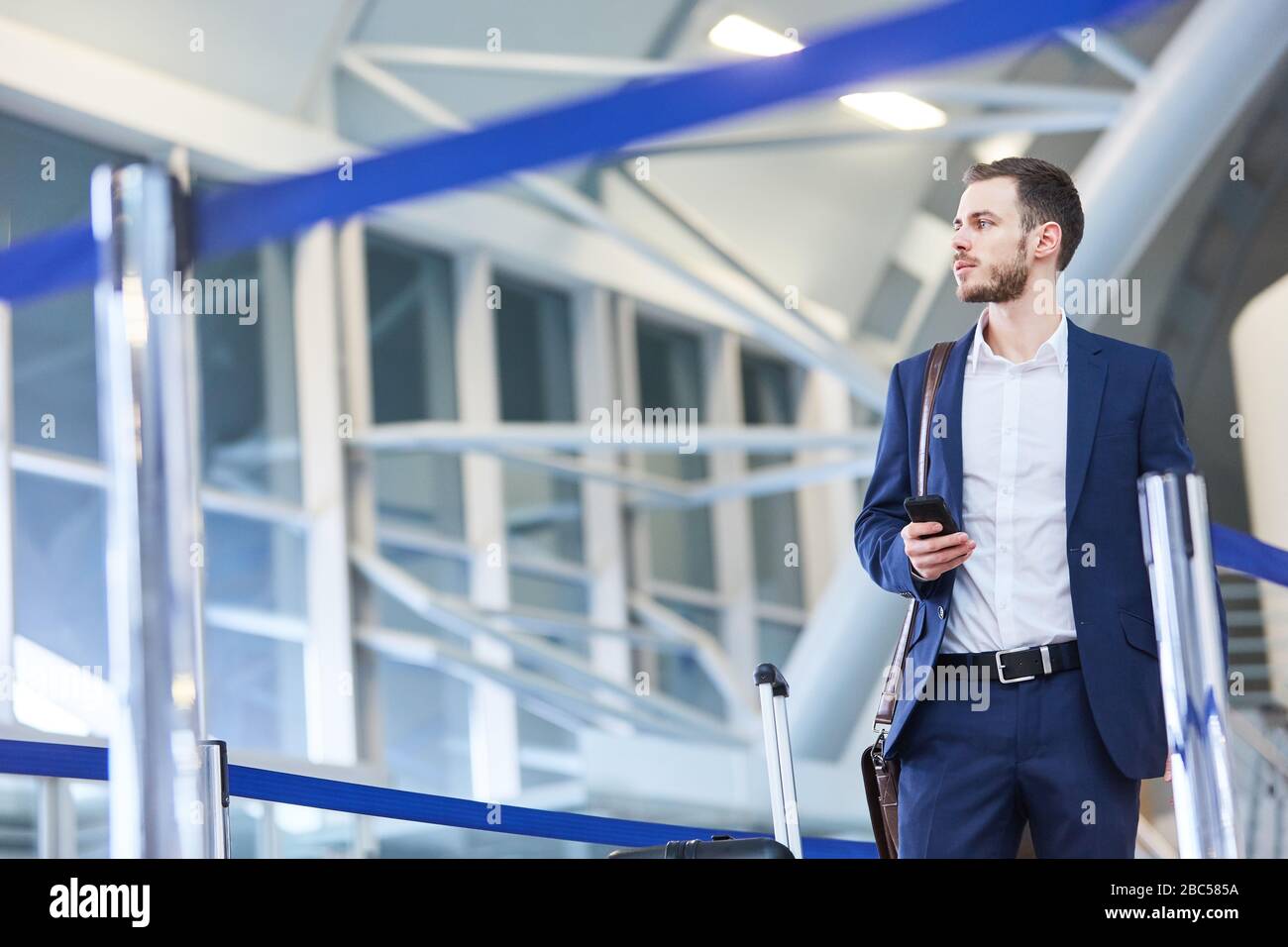 Un jeune homme d'affaires utilisant un smartphone au terminal de l'aéroport lors d'un voyage d'affaires Banque D'Images