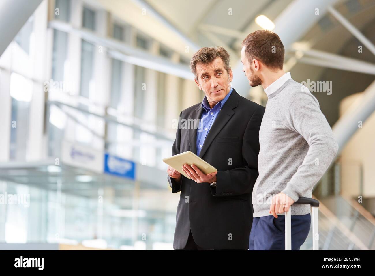 Deux personnes en voyage d'affaires utilisant des tablettes électroniques au terminal de l'aéroport avant un voyage d'affaires Banque D'Images