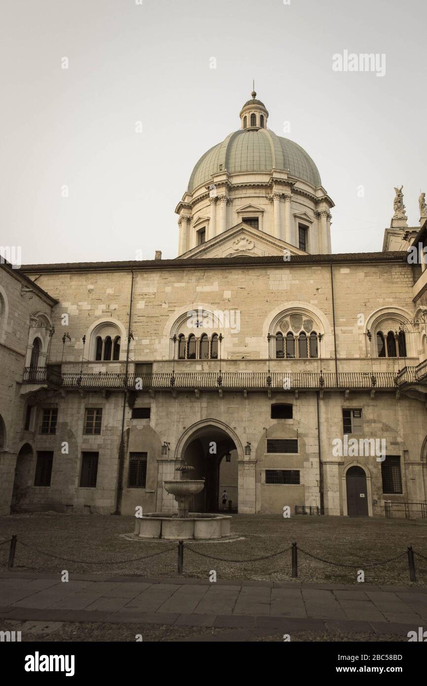 Brescia, Italie - 1 août 2018: La vue de la fontaine dans la cour intérieure du palais médiéval Palazzo del Broletto avec dôme de la nouvelle cathédrale sur b Banque D'Images