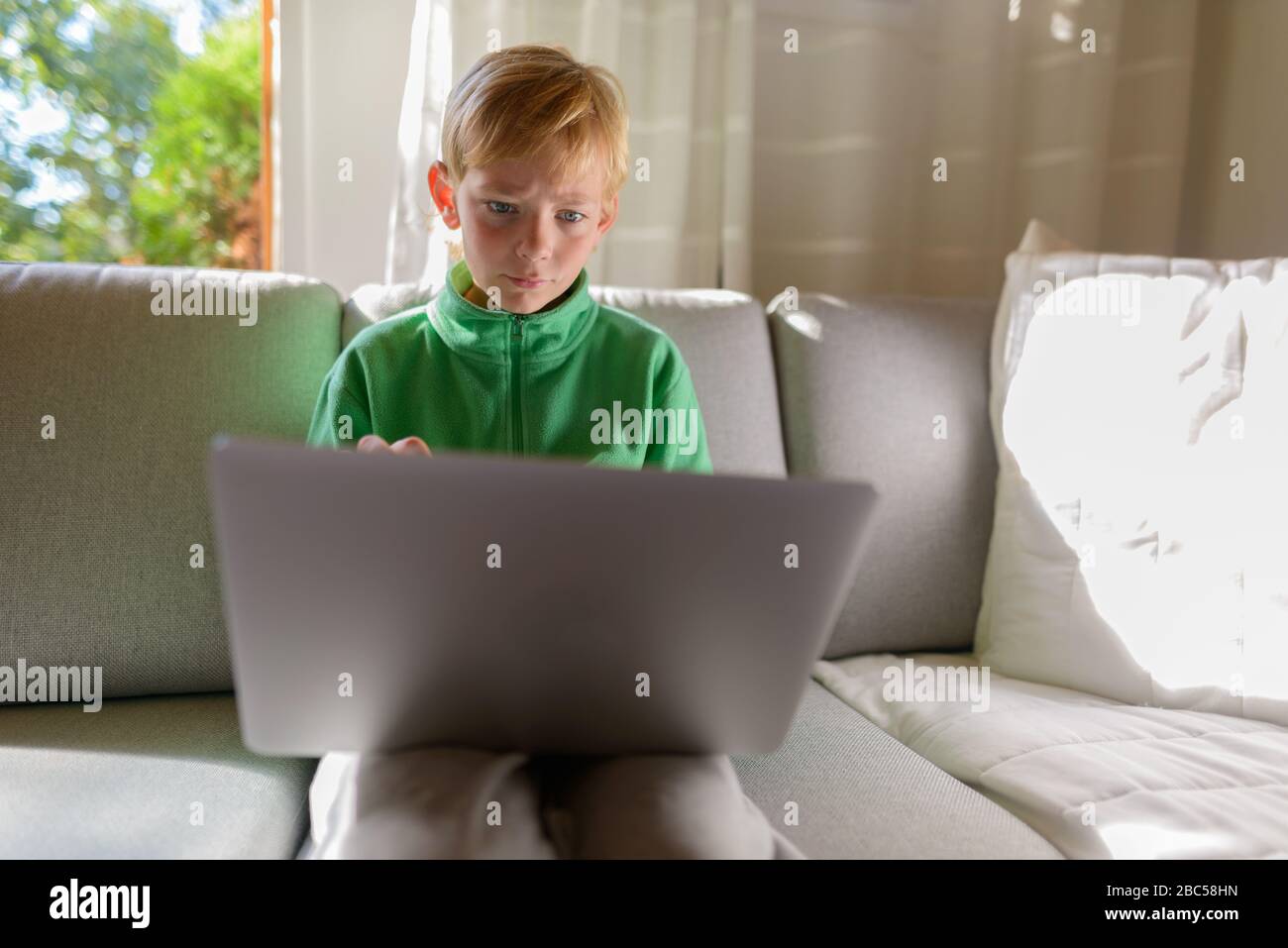 Jeune beau garçon utilisant un ordinateur portable sur le canapé à la maison Banque D'Images