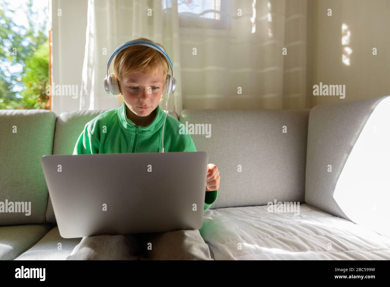 Jeune beau garçon avec casque utilisant un ordinateur portable à la maison Banque D'Images