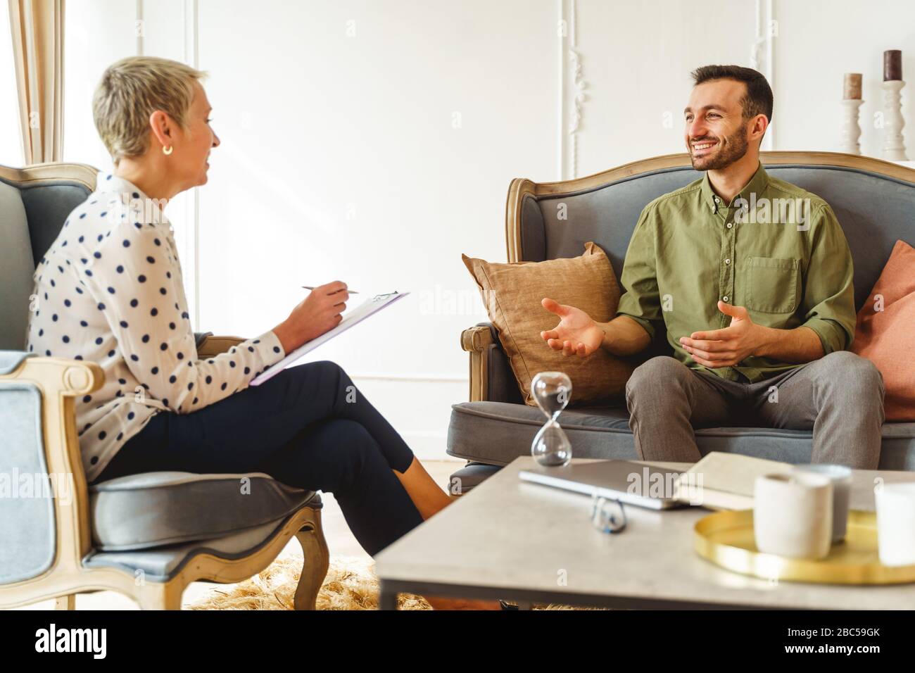 Homme souriant et souriant à sa psychanalyste féminine Banque D'Images