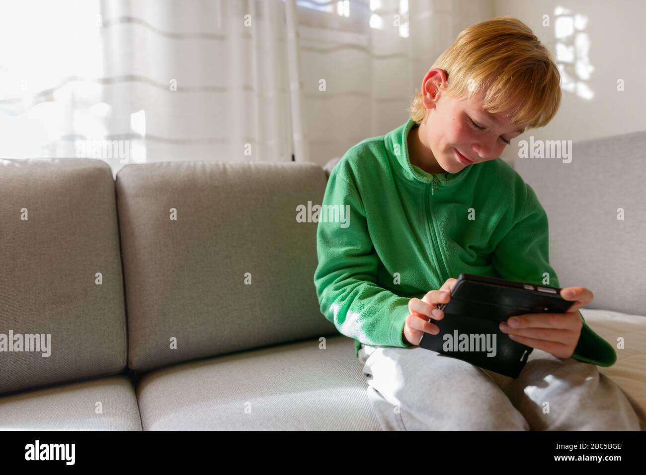 Joyeux jeune beau garçon utilisant le téléphone sur le canapé à la maison Banque D'Images