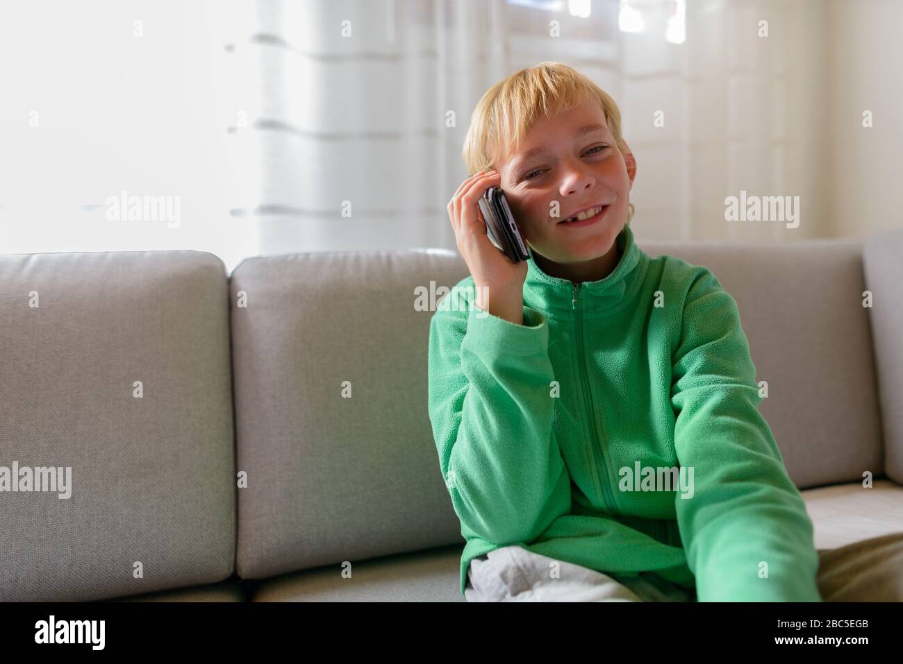Joyeux jeune beau garçon qui parle au téléphone à la maison Banque D'Images
