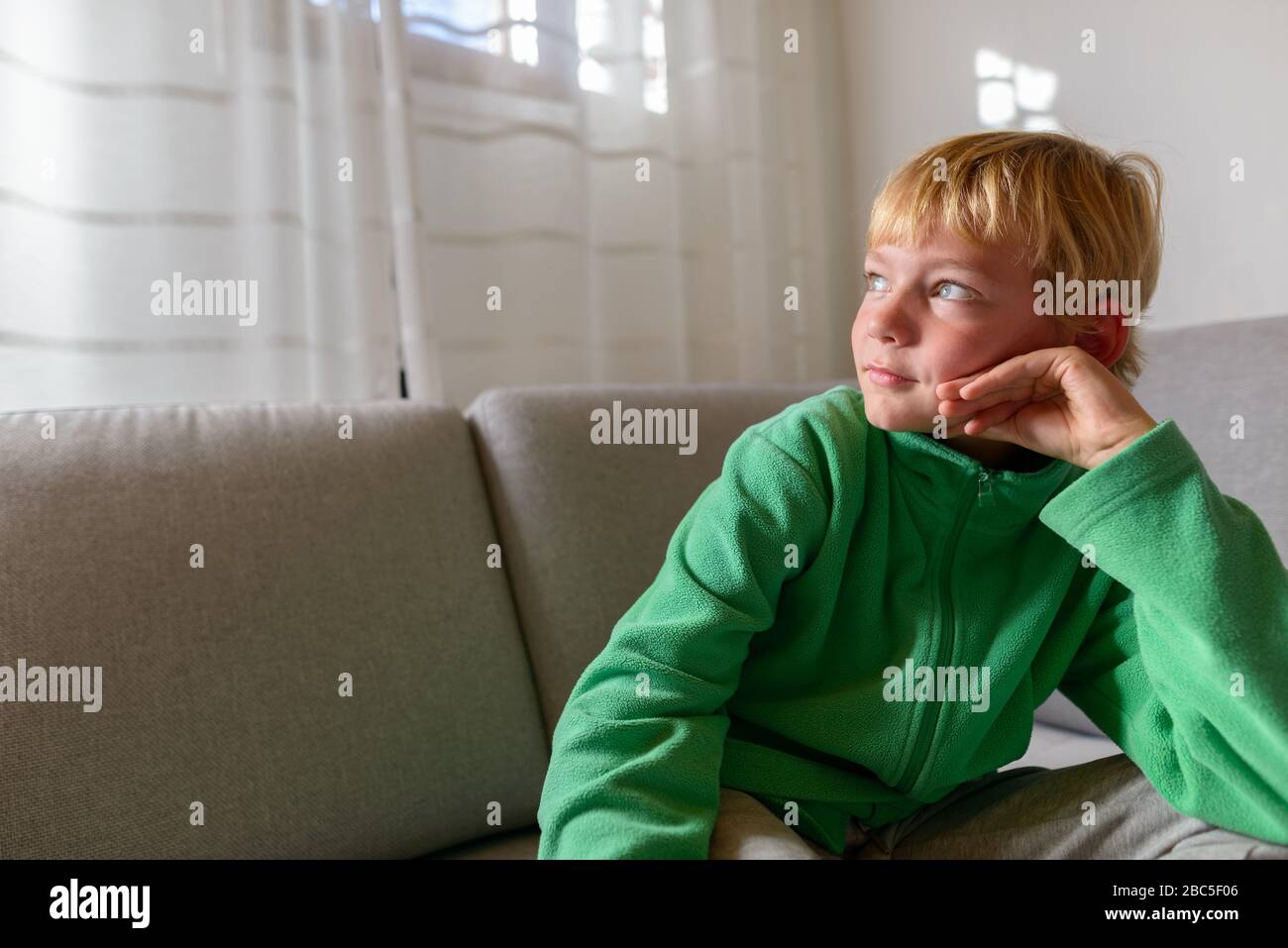 Jeune beau garçon pensant sur le canapé à la maison Banque D'Images