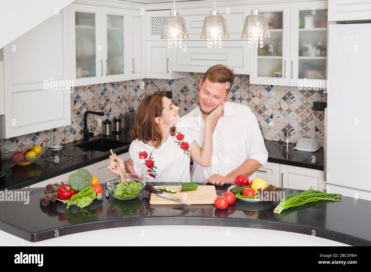 vegan jeune homme de famille et femme en chemise blanche pendant la cuisine à la maison pendant l'auto-isolation Banque D'Images