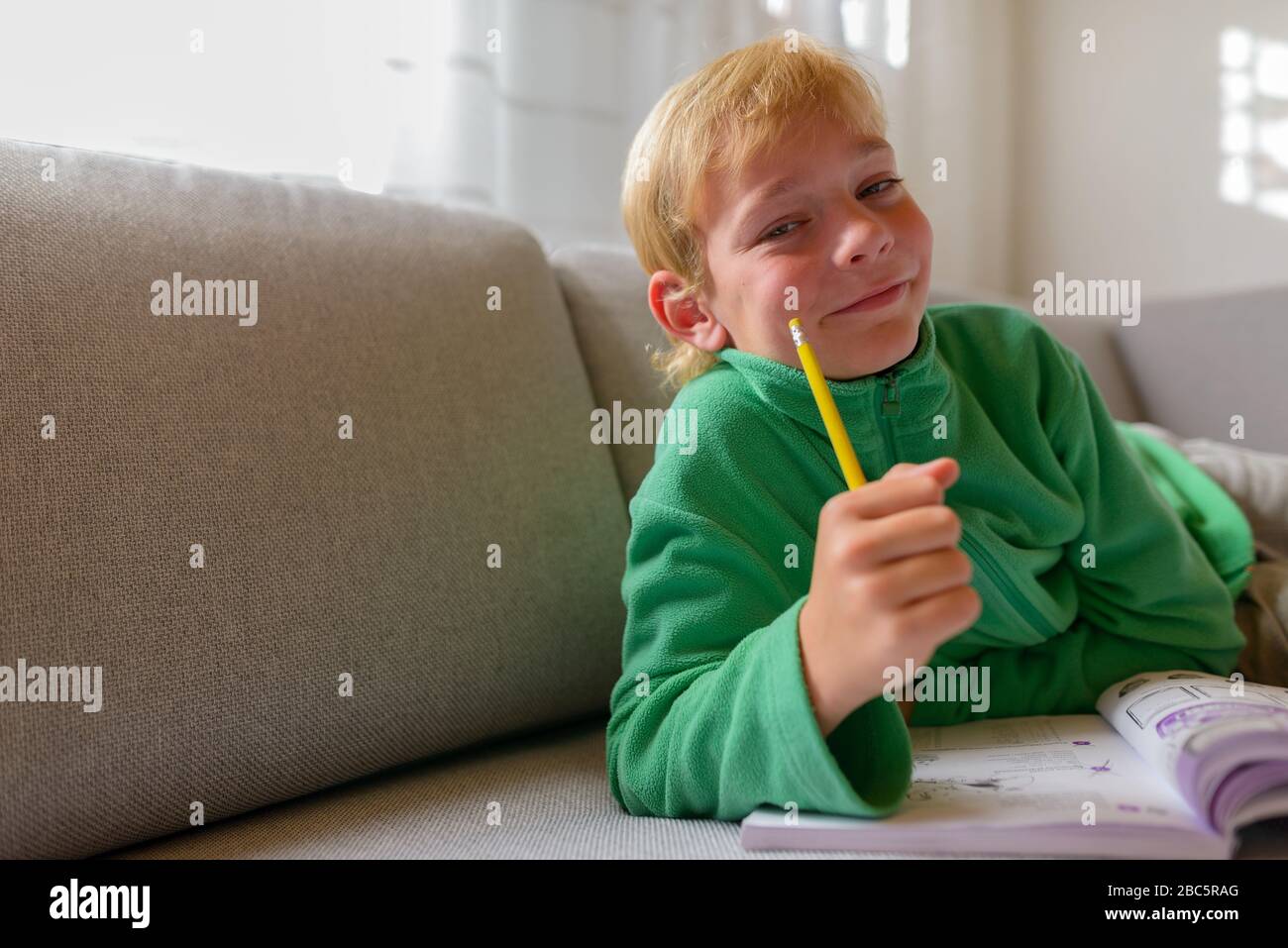 Joyeux jeune beau garçon étudiant sur le canapé à la maison Banque D'Images