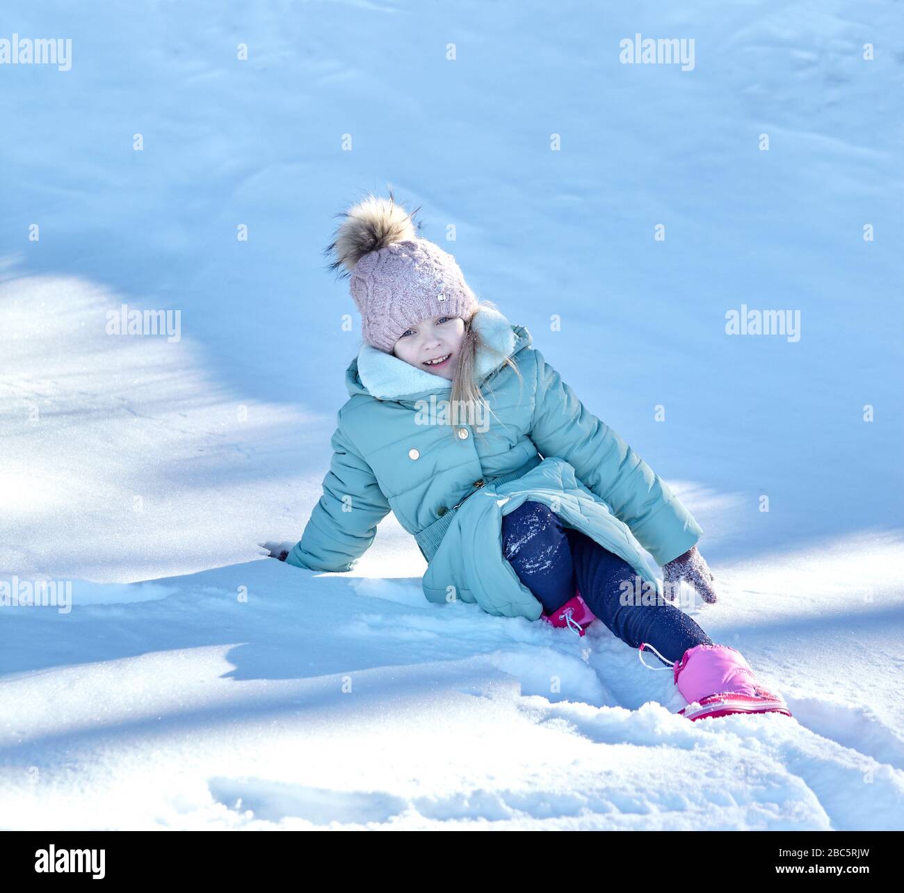 Petite fille fille dans des vêtements colorés jouant à l'extérieur. Loisirs actifs avec enfant en hiver par temps froid Banque D'Images