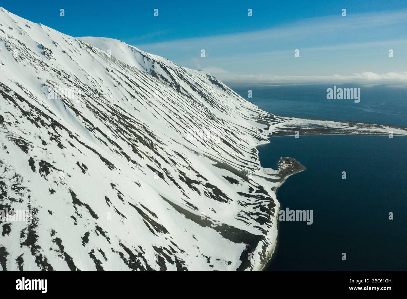 La côte montagneuse de la mer couverte de neige par un temps ensoleillé. Lieu de tournage sur la côte nord de la mer de Béring, région de Chukchi, Russie. Banque D'Images
