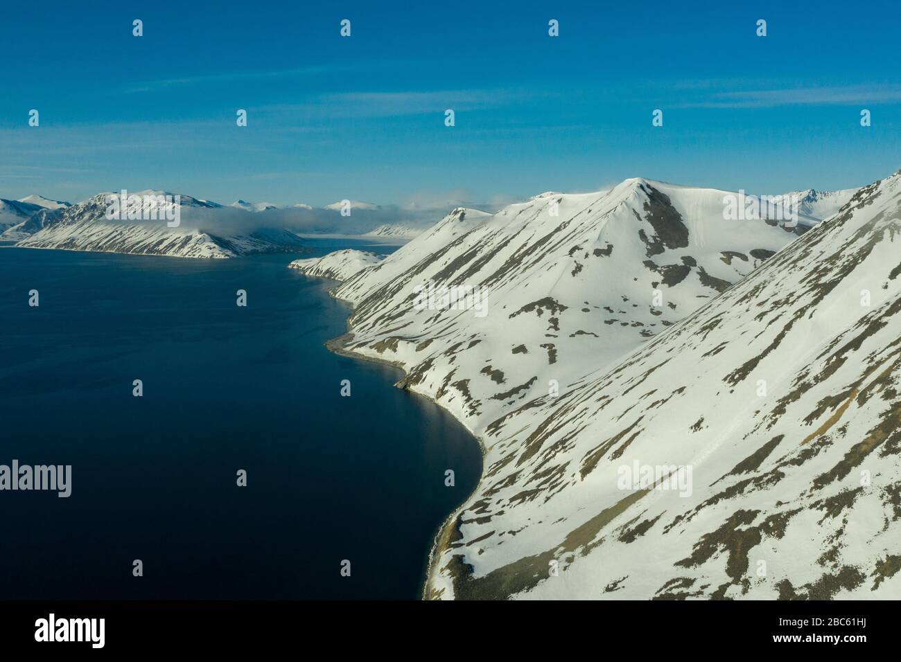 La côte montagneuse de la mer couverte de neige par un temps ensoleillé. Lieu de tournage sur la côte nord de la mer de Béring, région de Chukchi, Russie. Banque D'Images