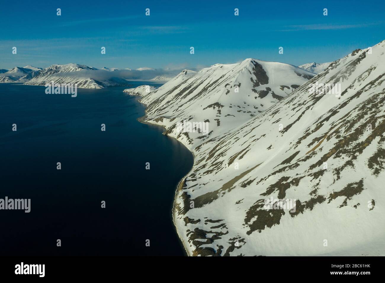 La côte montagneuse de la mer couverte de neige par un temps ensoleillé. Lieu de tournage sur la côte nord de la mer de Béring, région de Chukchi, Russie. Banque D'Images