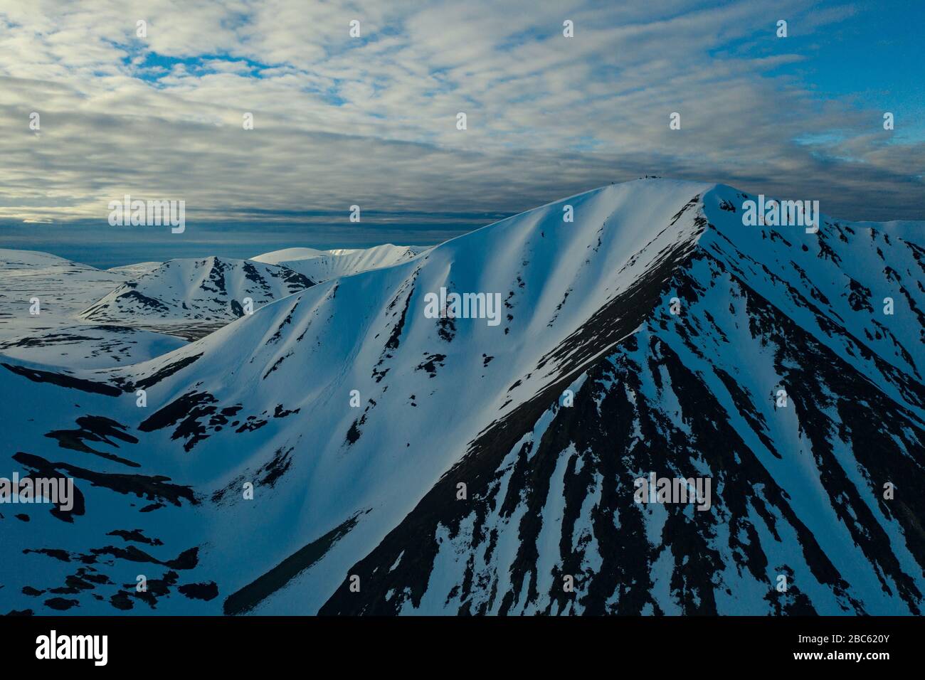 Les pentes des montagnes sont recouvertes de neige par temps nuageux. Lieu de tournage sur la côte nord de la mer de Béring, région de Chukchi, Russie. Banque D'Images