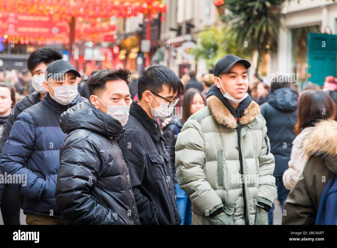 Les jeunes hommes asiatiques et orientaux portent des masques de visage, à l'occasion des célébrations de la nouvelle année chinoise en 2020 à Chinatown, Londres, à la suite des rapports de l'éclosion de coronavirus Banque D'Images