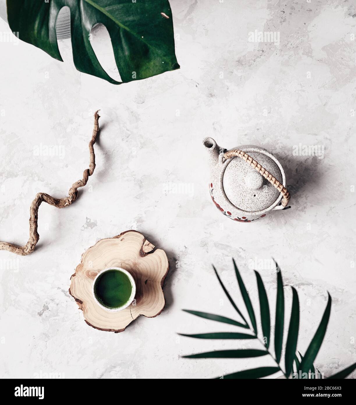 Le thé vert en poudre japonais traditionnel de Matcha dans une tasse près de la théière et des plantes lors de la cérémonie du thé se fait sur fond de marbre blanc Banque D'Images