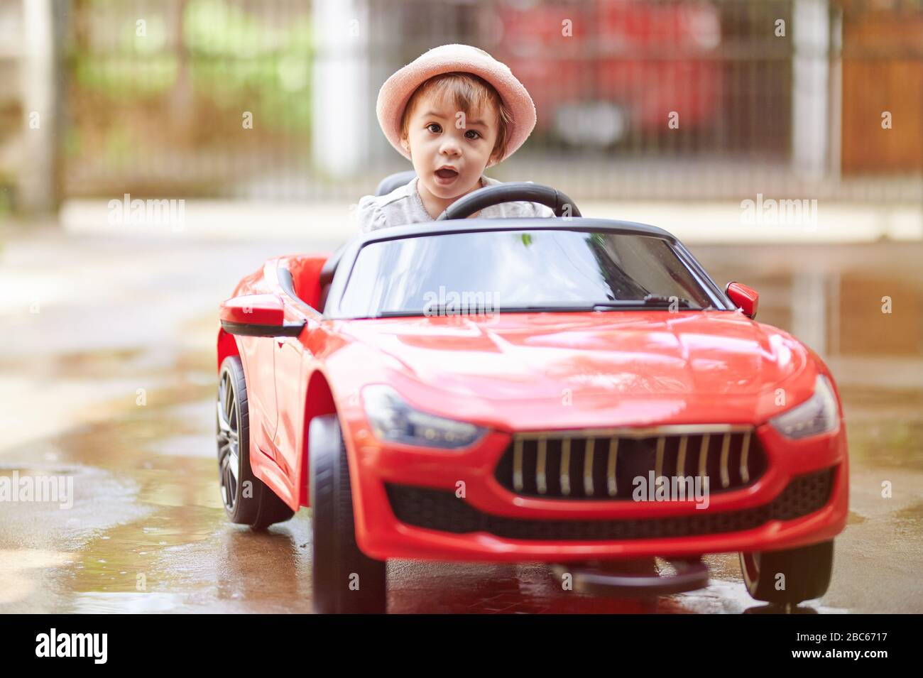 Baby girl Ride jouet voiture et regarder dans l'appareil photo sur fond ensoleillé de parc Banque D'Images