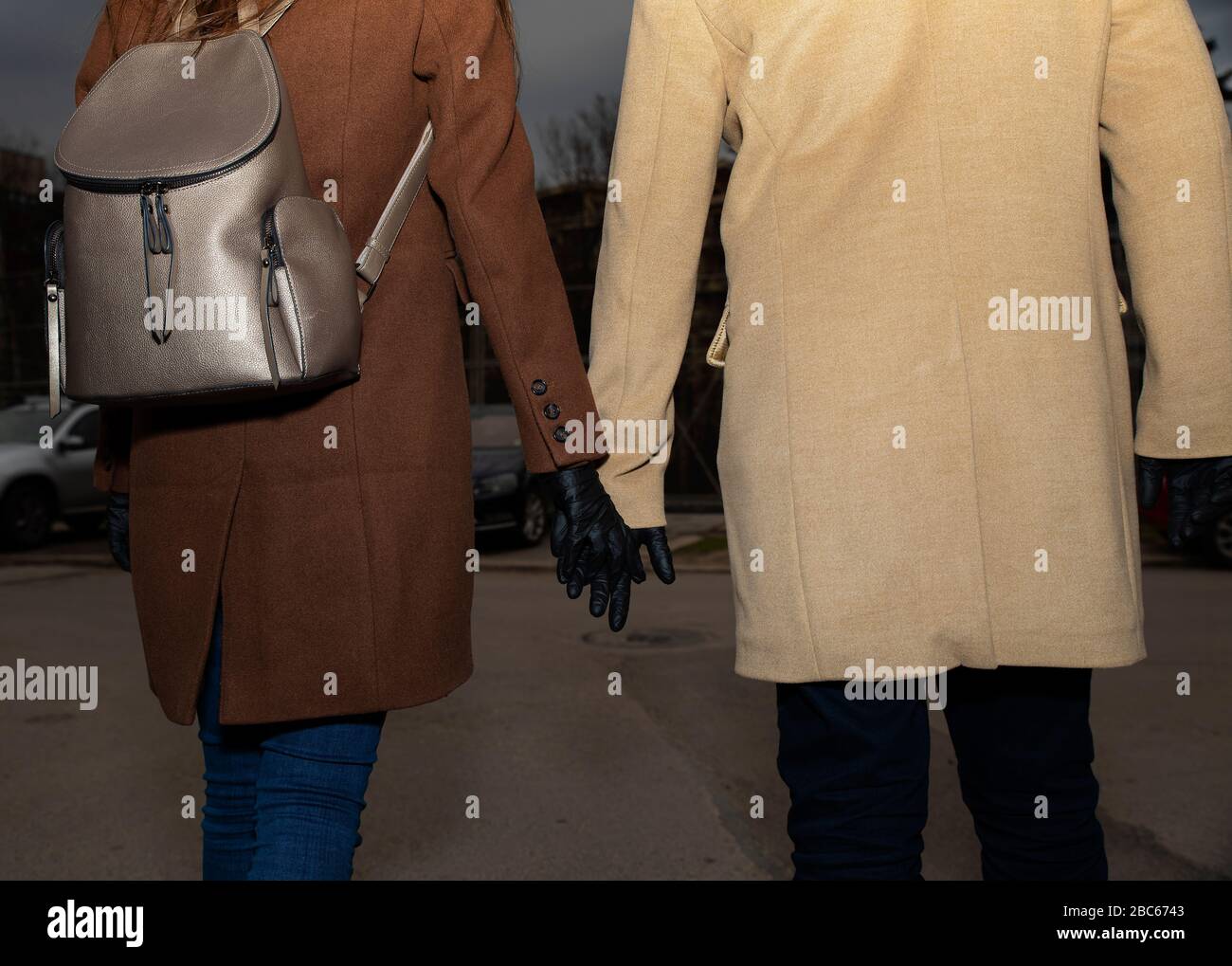 Couple portant des gants en nitrile noirs marchant dans la rue et tenant leurs mains mise au point sélective Banque D'Images